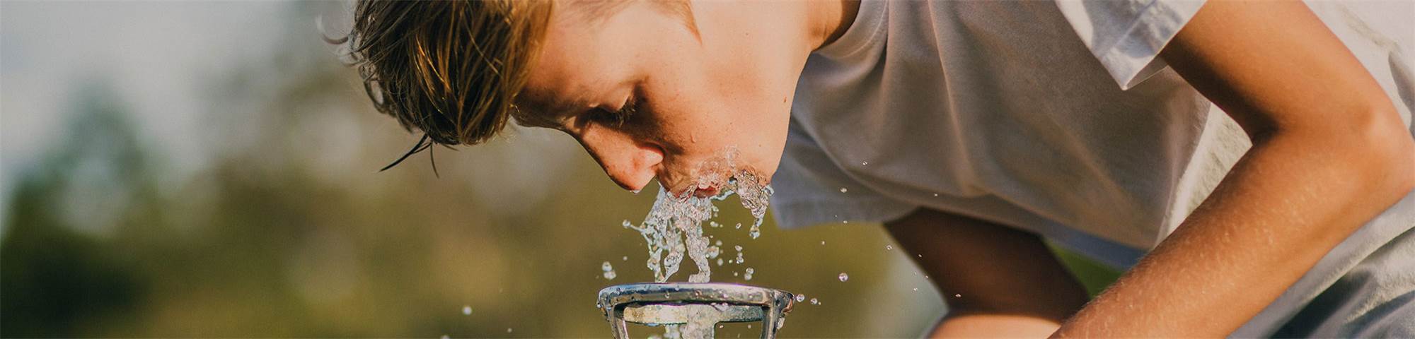 young guy drinking water from a little fountain