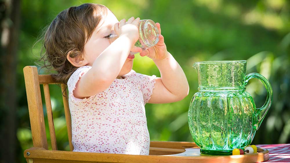 Enfant buvant un verre d'eau dans une chaise enfant