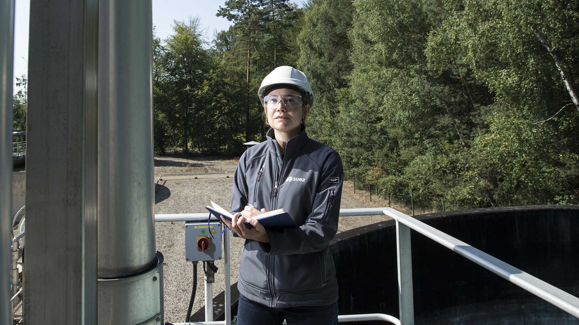 Collaboratrice inspectant une conduite d'eau sur un site industriel